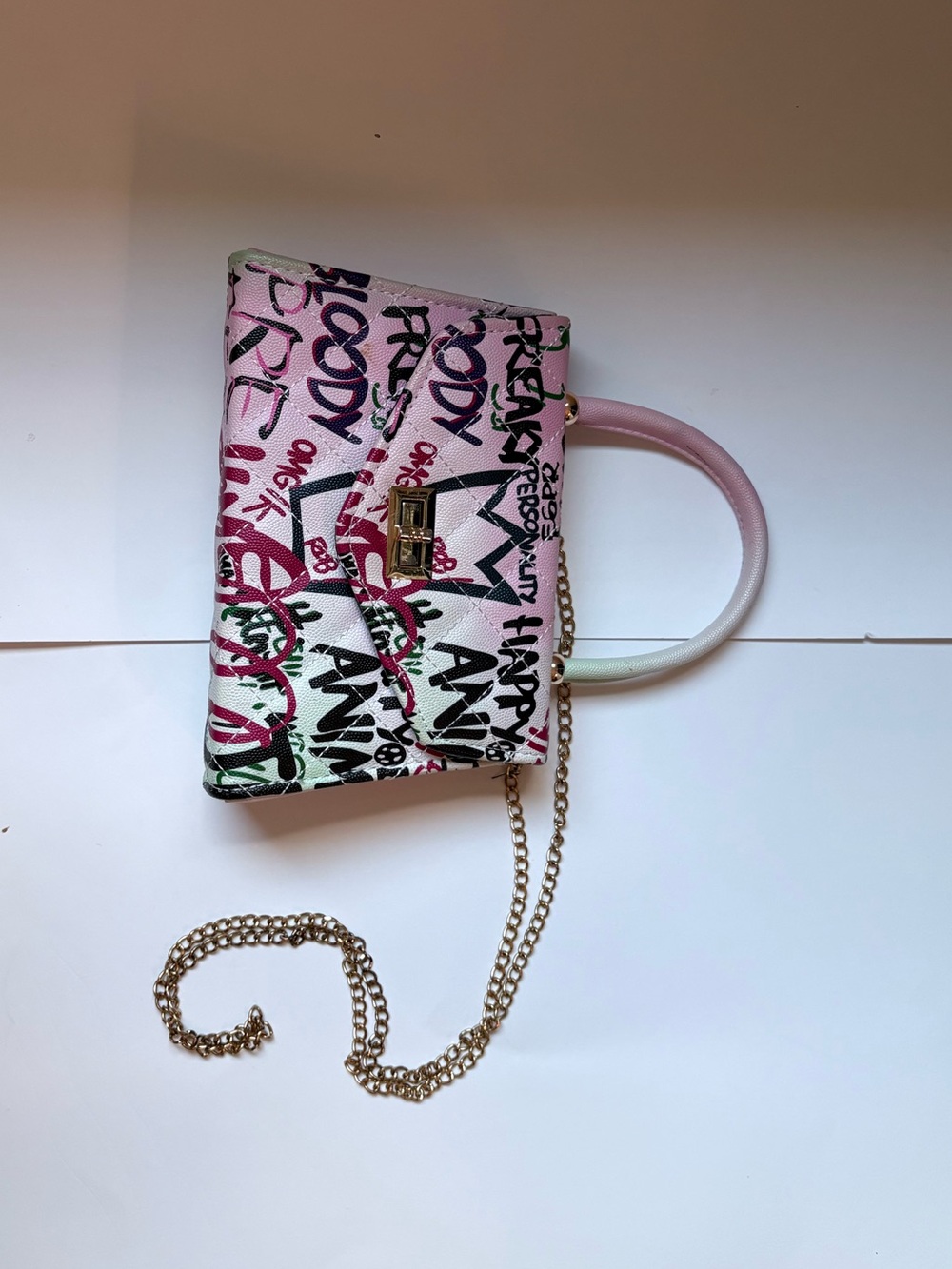 Adorable graffiti purse. Gold chain strap and white and multicolor print detail.